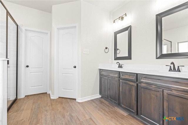 bathroom with walk in shower, vanity, and hardwood / wood-style flooring