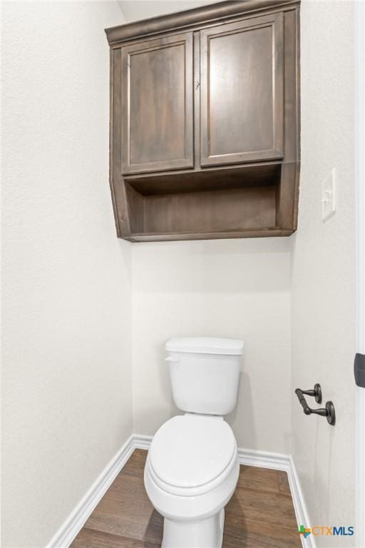 bathroom with hardwood / wood-style flooring and toilet