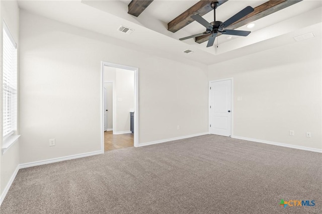 empty room featuring beamed ceiling, ceiling fan, light colored carpet, and a wealth of natural light