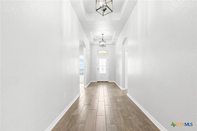 entryway with a tray ceiling and a chandelier