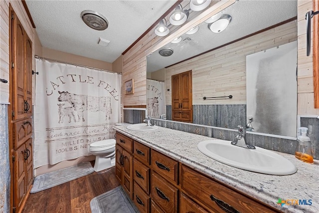 bathroom with a textured ceiling, hardwood / wood-style flooring, toilet, and wooden walls