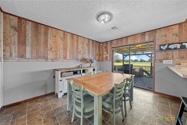 dining area with a textured ceiling and wood walls