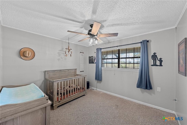 carpeted bedroom featuring a crib, a textured ceiling, ceiling fan, and ornamental molding