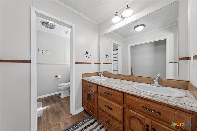 bathroom with hardwood / wood-style floors, vanity, crown molding, toilet, and a textured ceiling