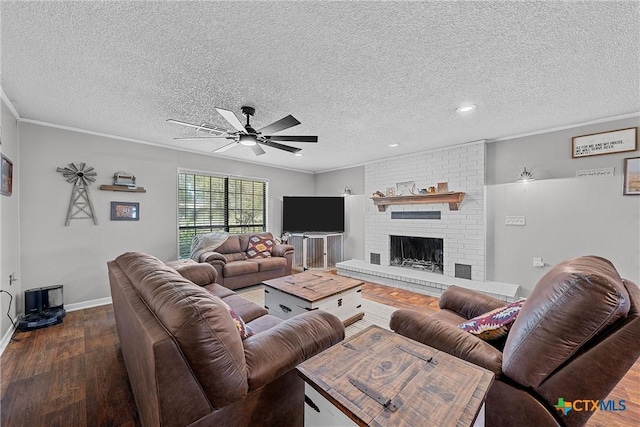 living room with ornamental molding, a textured ceiling, ceiling fan, a fireplace, and dark hardwood / wood-style floors