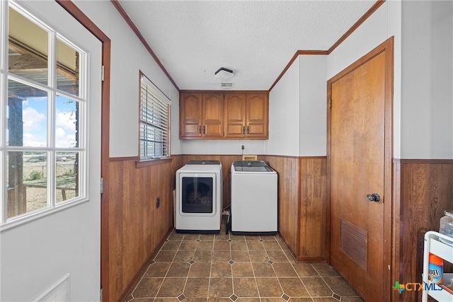 clothes washing area featuring a healthy amount of sunlight, cabinets, independent washer and dryer, and a textured ceiling