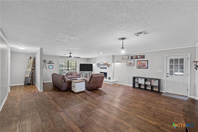 unfurnished living room with ornamental molding, a textured ceiling, ceiling fan, a fireplace, and dark hardwood / wood-style floors