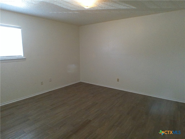 spare room featuring dark wood-type flooring and a textured ceiling