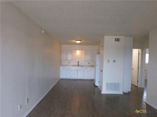 507 Hackberry St, Copperas Cove, TX 76522 - kitchen featuring freestanding refrigerator, white cabinets, dark wood-style flooring, light countertops, and a textured ceiling