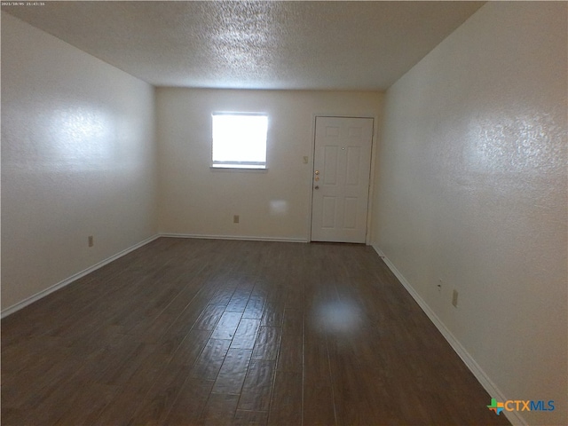 empty room with a textured ceiling and dark hardwood / wood-style flooring