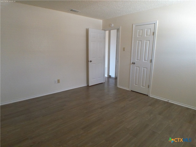 unfurnished room featuring dark wood-type flooring and a textured ceiling