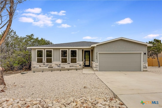 ranch-style home with fence, driveway, a shingled roof, stone siding, and a garage