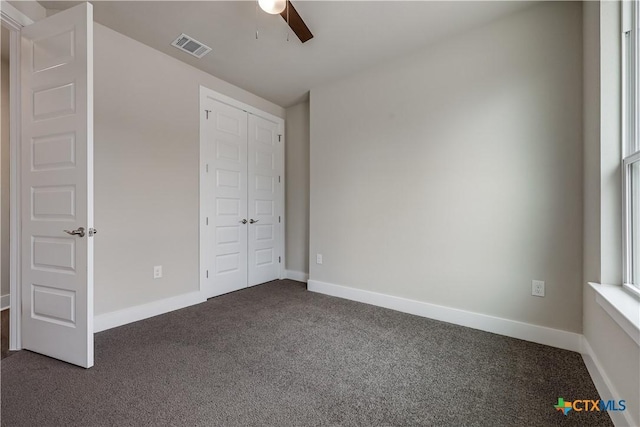 unfurnished bedroom featuring a closet, visible vents, baseboards, and dark colored carpet