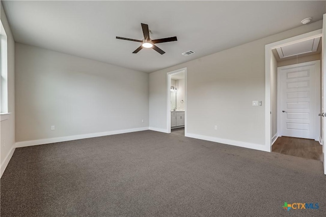 unfurnished bedroom featuring visible vents, ensuite bathroom, dark carpet, baseboards, and attic access