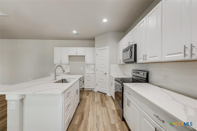 kitchen with white cabinetry, sink, appliances with stainless steel finishes, and an island with sink