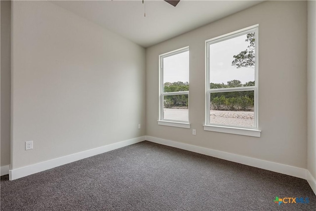 spare room with dark carpet, a ceiling fan, and baseboards