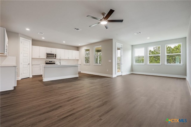 unfurnished living room with visible vents, baseboards, and dark wood finished floors