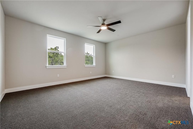 empty room featuring dark colored carpet, baseboards, and ceiling fan