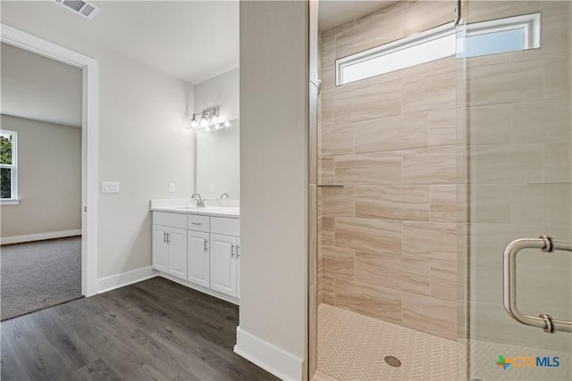 bathroom featuring visible vents, baseboards, wood finished floors, and a shower stall