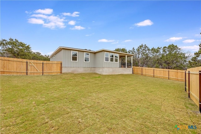 rear view of property featuring a lawn and a fenced backyard