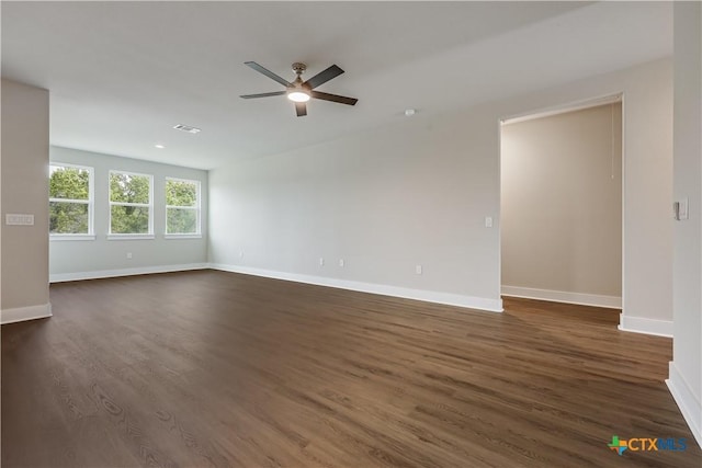 spare room featuring visible vents, baseboards, dark wood-type flooring, and ceiling fan