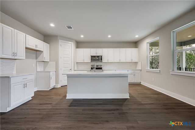 kitchen with appliances with stainless steel finishes, white cabinets, dark wood finished floors, and light countertops