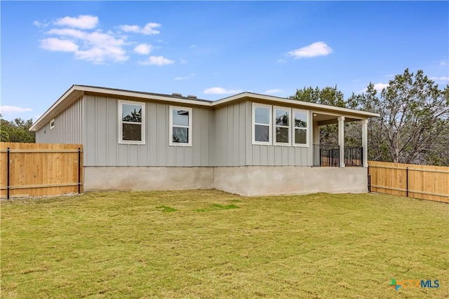 rear view of house with a lawn, board and batten siding, and fence private yard