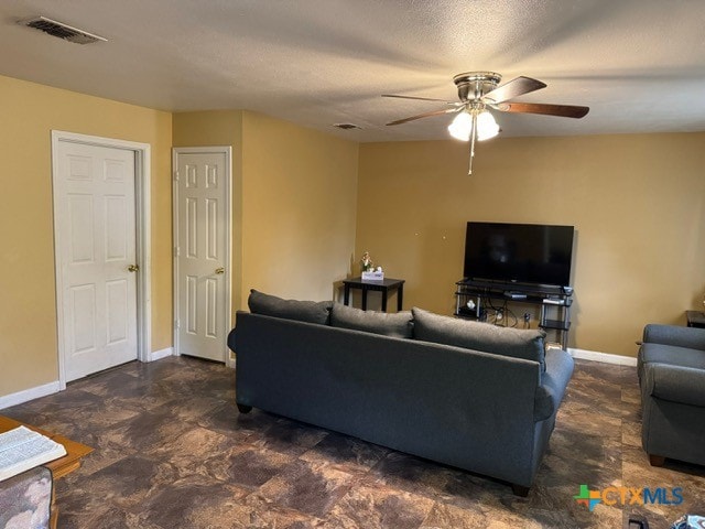 living room with ceiling fan and a textured ceiling