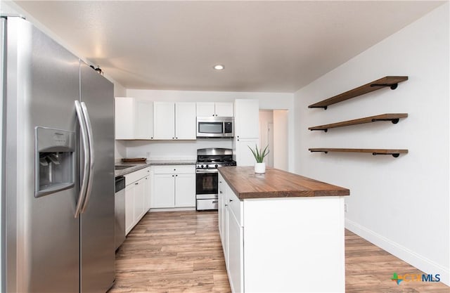 kitchen featuring white cabinets, a center island, stainless steel appliances, and wood counters