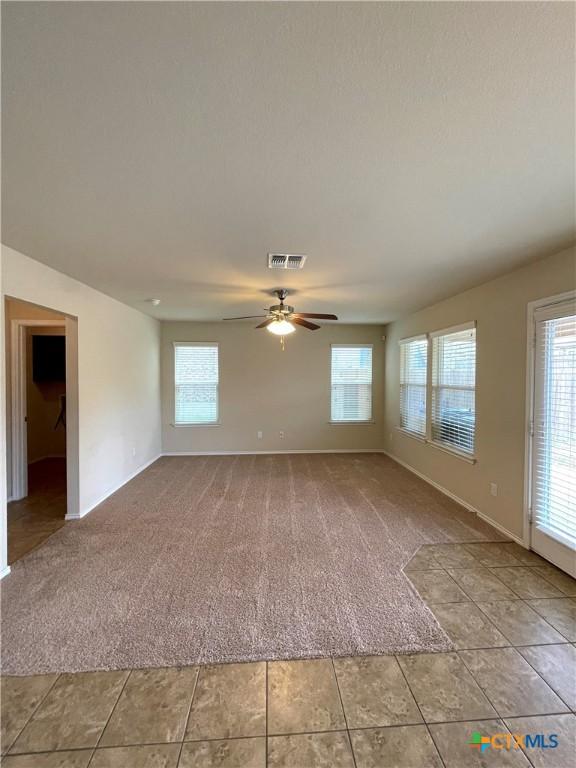 unfurnished living room featuring light carpet and ceiling fan