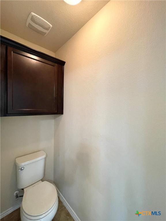 bathroom with tile patterned flooring, a textured ceiling, and toilet