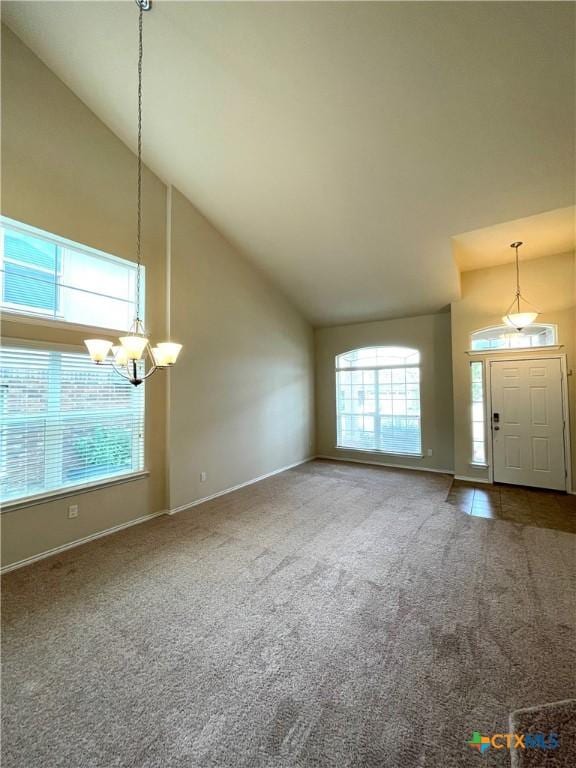 unfurnished living room featuring carpet, a chandelier, and high vaulted ceiling