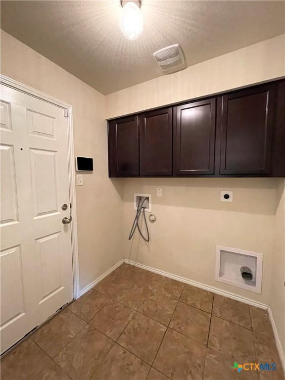 laundry room with electric dryer hookup, cabinets, gas dryer hookup, hookup for a washing machine, and a textured ceiling