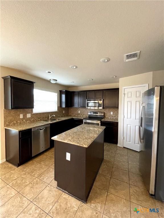 kitchen with a kitchen island, light tile patterned floors, sink, and appliances with stainless steel finishes