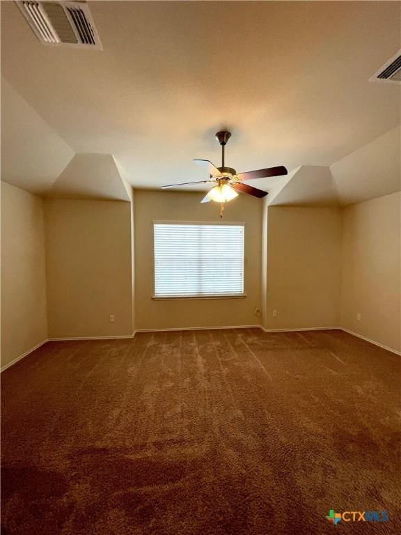 empty room with dark colored carpet, ceiling fan, and vaulted ceiling