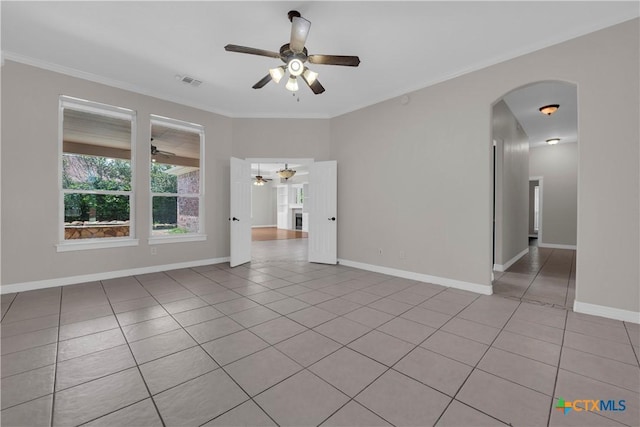 tiled empty room with ceiling fan and ornamental molding