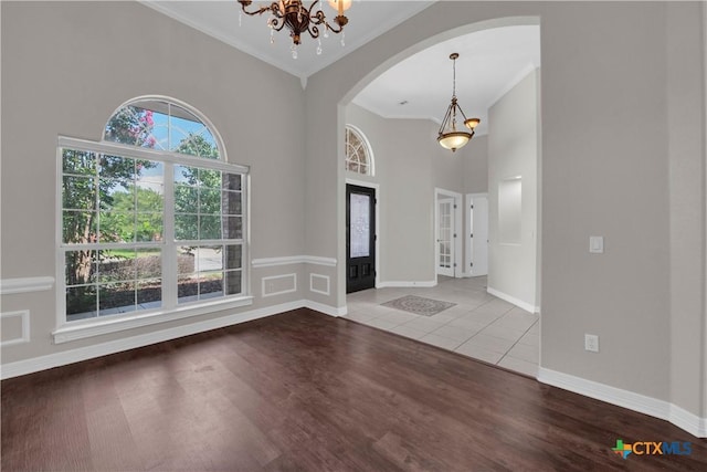 entrance foyer with wood-type flooring, a chandelier, and ornamental molding