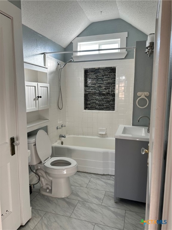 full bathroom with vanity, tiled shower / bath, vaulted ceiling, toilet, and a textured ceiling