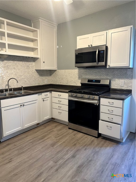 kitchen featuring light wood-type flooring, stainless steel appliances, white cabinetry, and sink