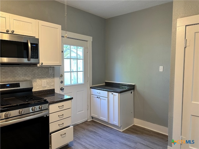 kitchen featuring decorative backsplash, white cabinetry, dark hardwood / wood-style flooring, and appliances with stainless steel finishes