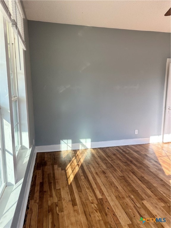 empty room with hardwood / wood-style floors and a textured ceiling