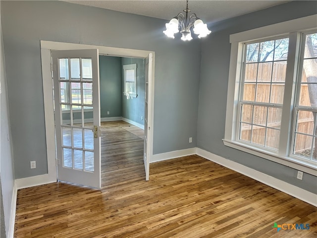 unfurnished dining area with hardwood / wood-style flooring, a textured ceiling, and a chandelier