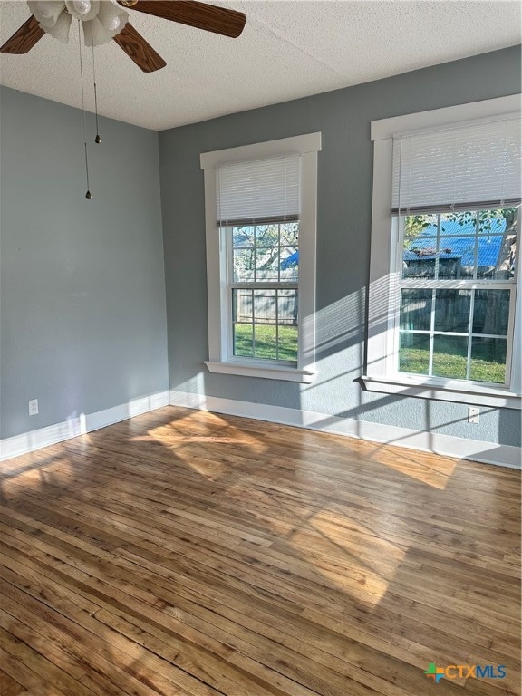 unfurnished room featuring ceiling fan, wood-type flooring, and a textured ceiling