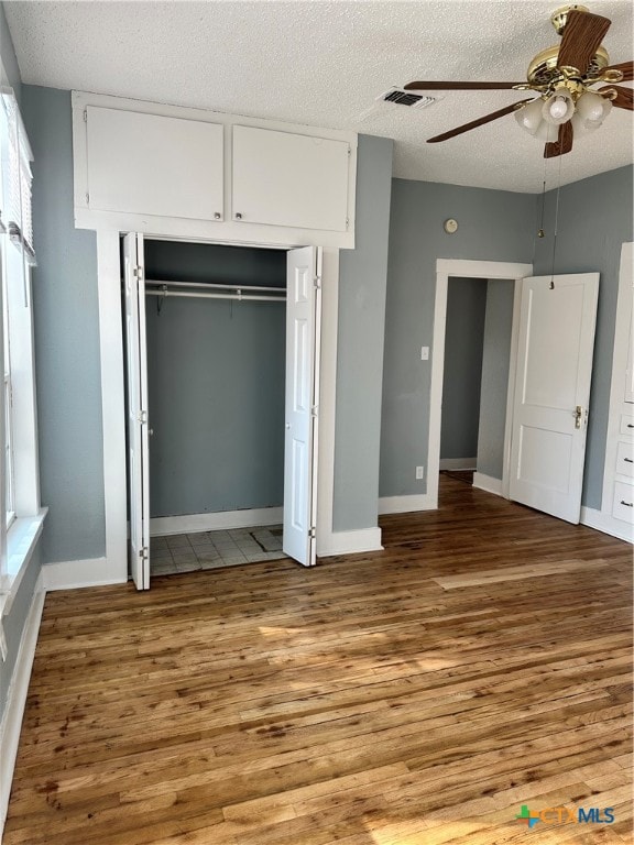 unfurnished bedroom with multiple windows, a textured ceiling, light hardwood / wood-style floors, and ceiling fan