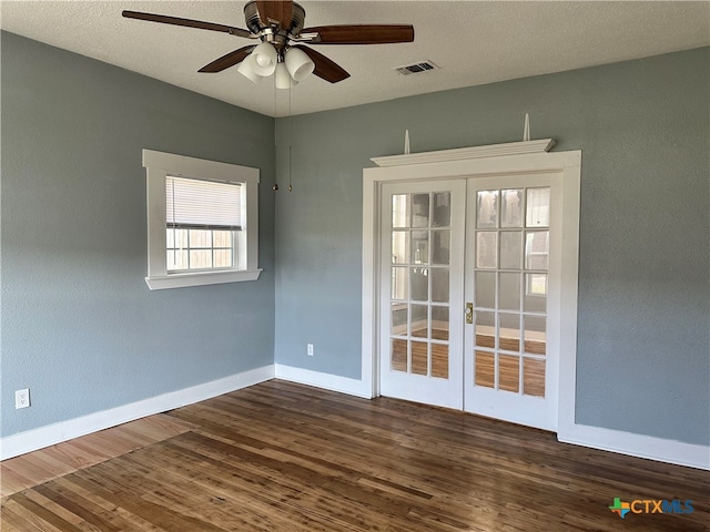 empty room with ceiling fan, dark hardwood / wood-style flooring, a textured ceiling, and french doors