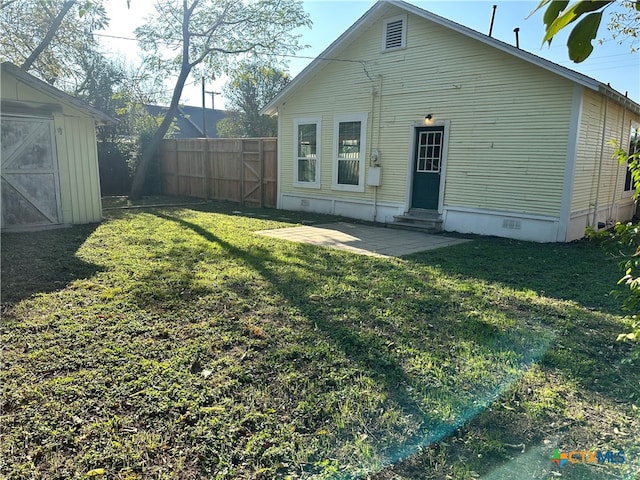 rear view of property with a lawn, a storage shed, and a patio