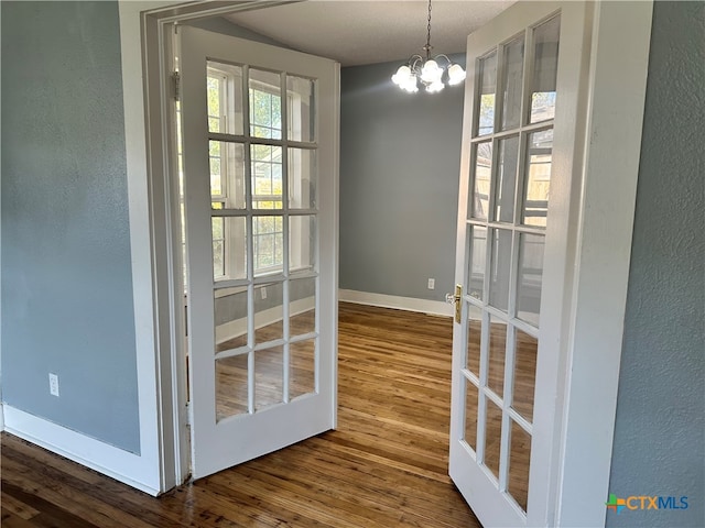 unfurnished dining area featuring hardwood / wood-style floors, an inviting chandelier, and french doors