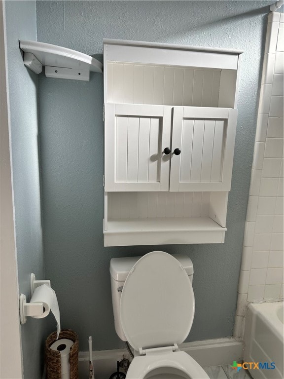 bathroom with a washtub and toilet