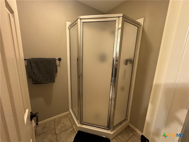 bathroom with an enclosed shower and tile patterned floors