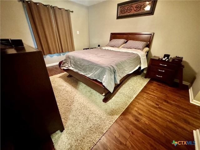 bedroom with dark hardwood / wood-style floors